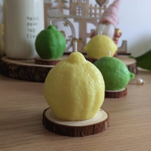 Bougie citron vert et jaune en cire de soja, citron jaune sur support en bois naturel devant une déco de Noël