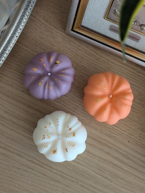 Bougies citrouilles violette, orange et blanche posées sur bois