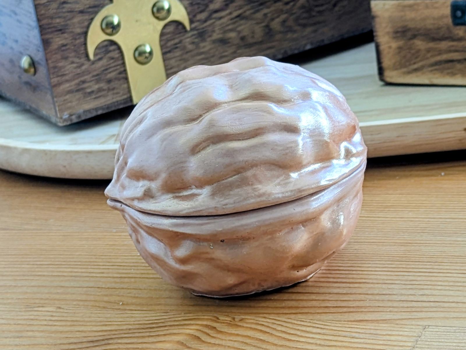 Bougie noix en plâtre verni posée devant un coffret en bois ancien