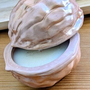 Coque de noix en plâtre entrouverte sur sa bougie en cire de soja, reflets dorés