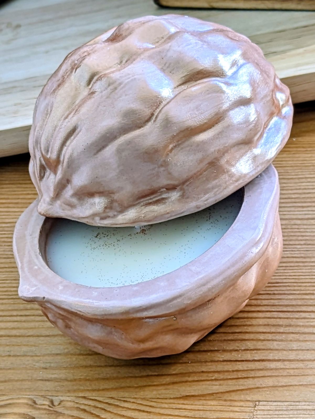 Coque de noix en plâtre entrouverte sur sa bougie en cire de soja, reflets dorés