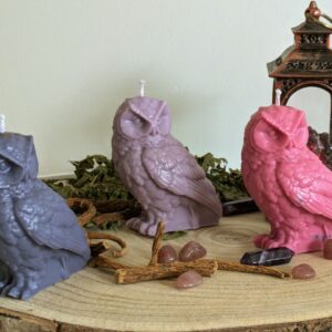 Bougie hibou en cire de soja en trois couleurs, bleue, violette et rose, sur une rondelle de bois avec des pierres