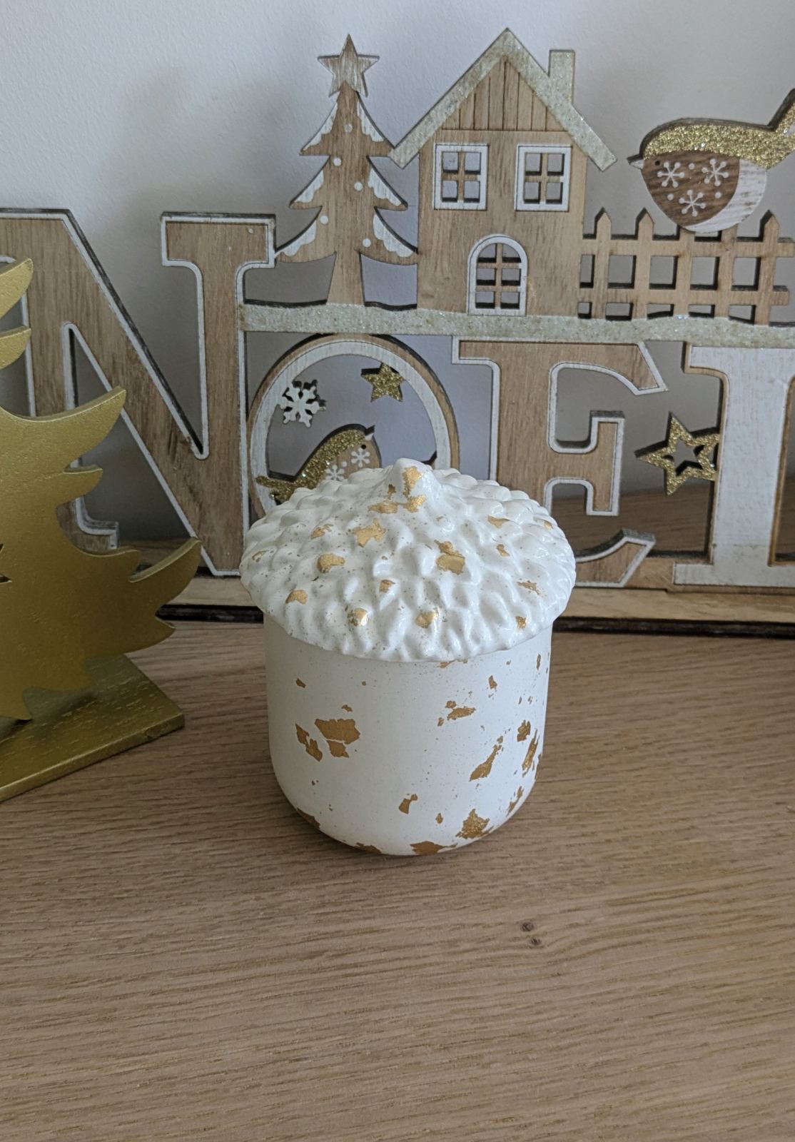 Bougie gland à couvercle fermée devant une déco de Noël