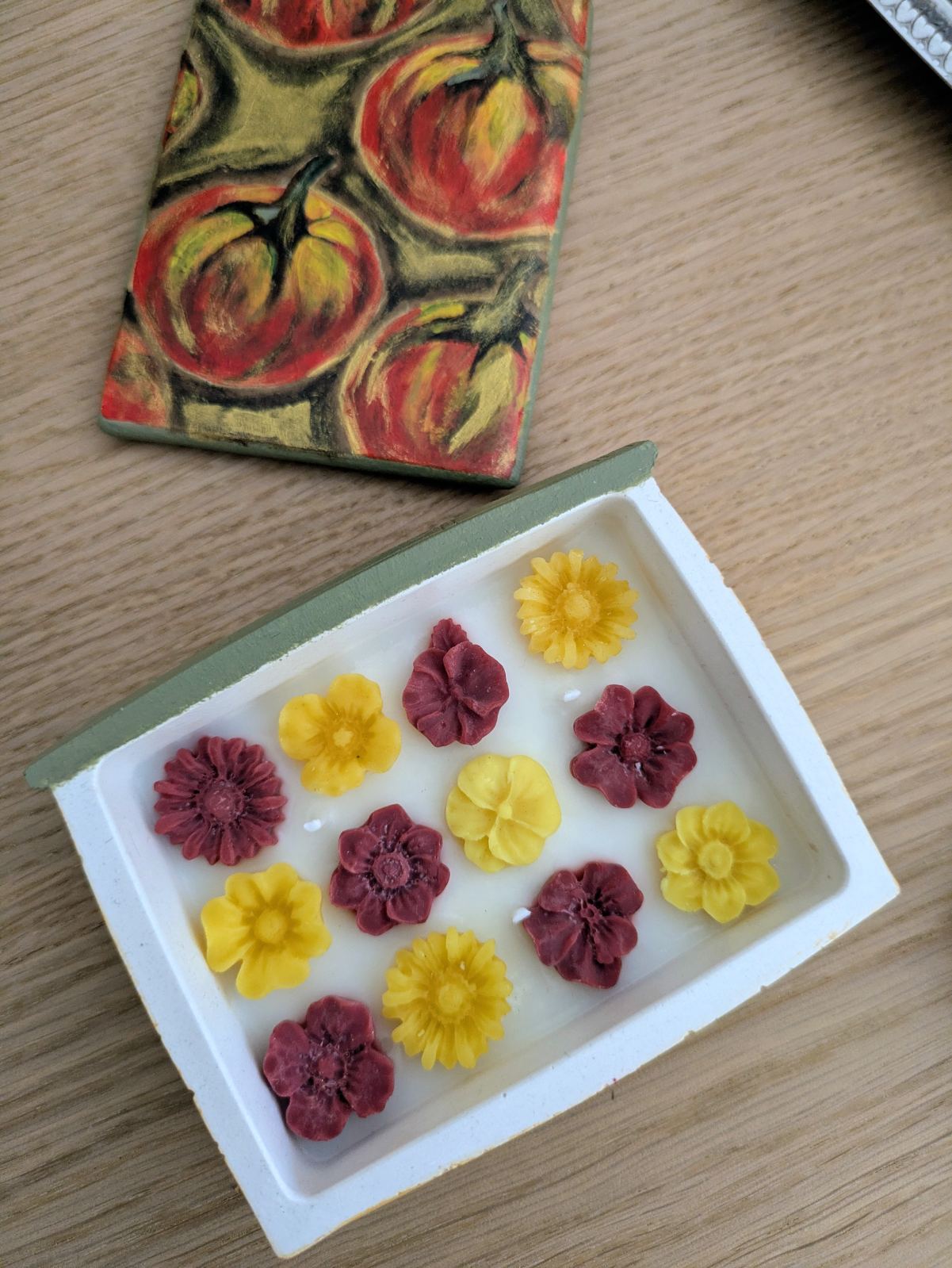 Fleurs de cire jaunes et bordeaux de la grande bougie livre vues de dessus, avec le couvercle