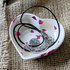 Plateau cœur rose en plâtre blanc à feuilles rose métallique, avec un collier posé dedans