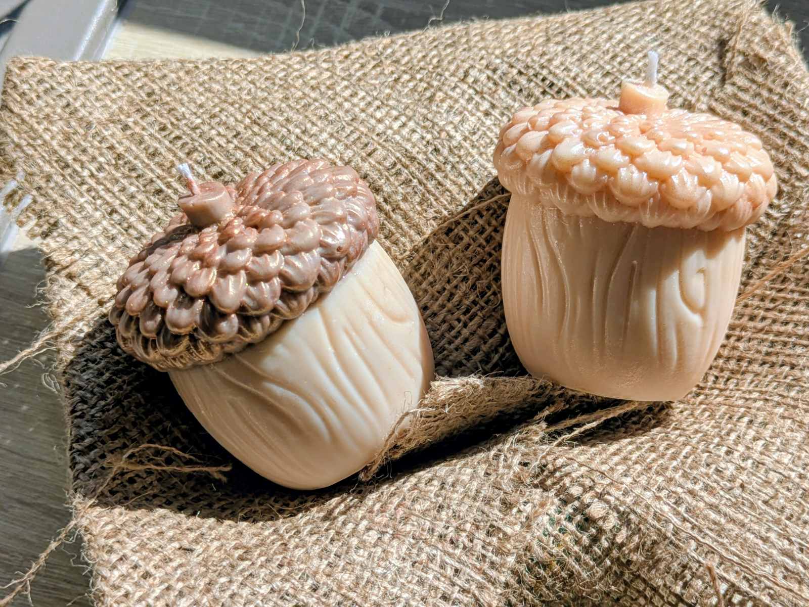 Deux bougies gland posées sur de la toile de jute, effet nacré sur le chapeau
