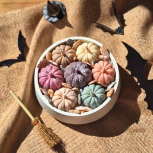 Bougie bouquet citrouilles pastel dans un bougeoir en plâtre naturel avec chapeau et balai de sorcière