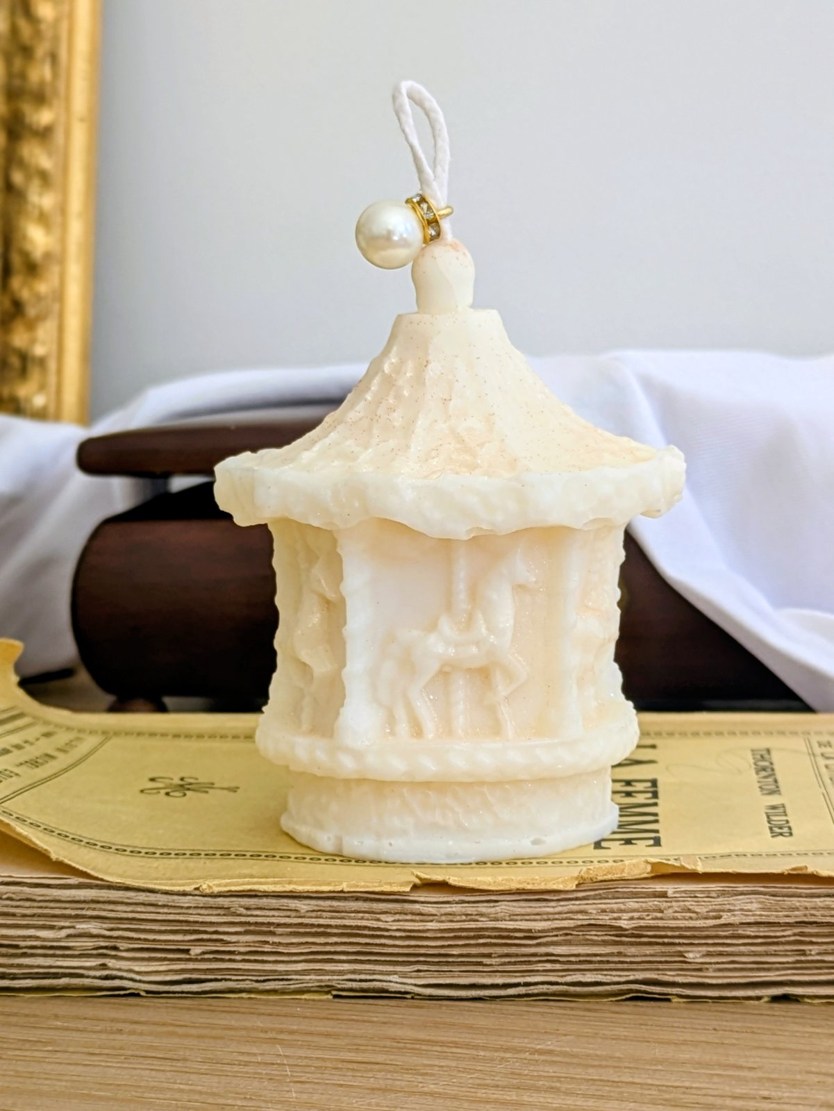 Bougie manège beige crème posée sur un vieux livre, décoration vintage