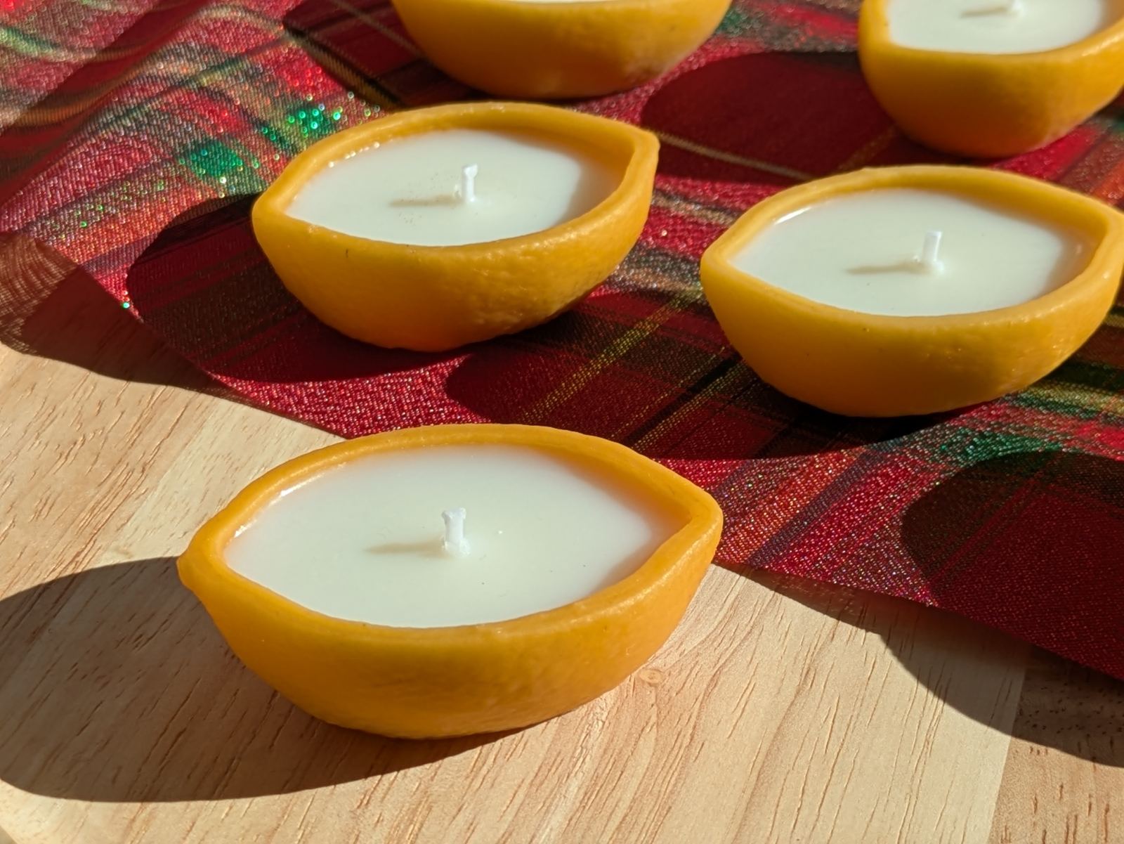 Bougies citron sur une table en bois et un tissu écossais rouge et vert