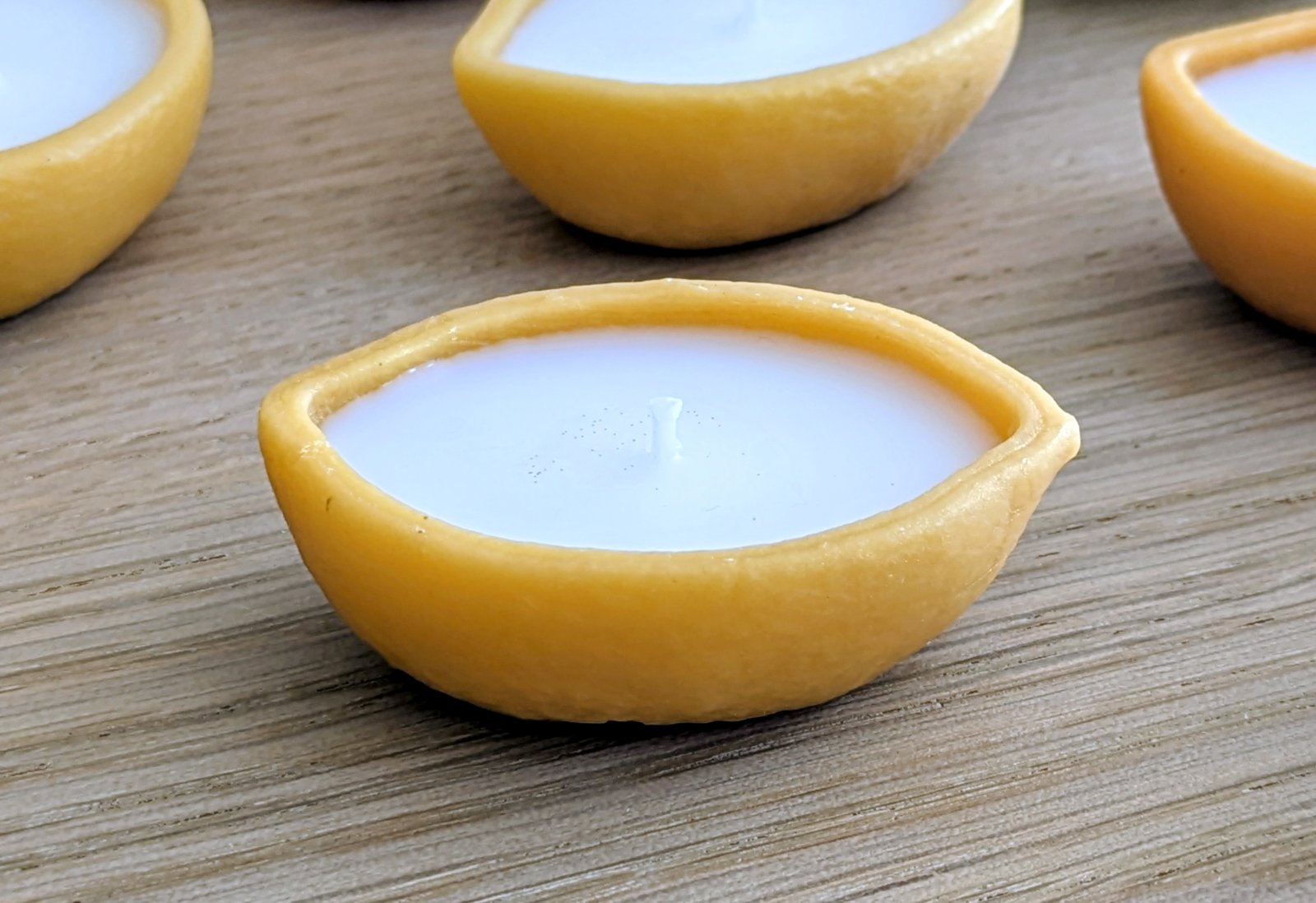 Bougie citron trompe-l'œil vue de profil sur une table en bois