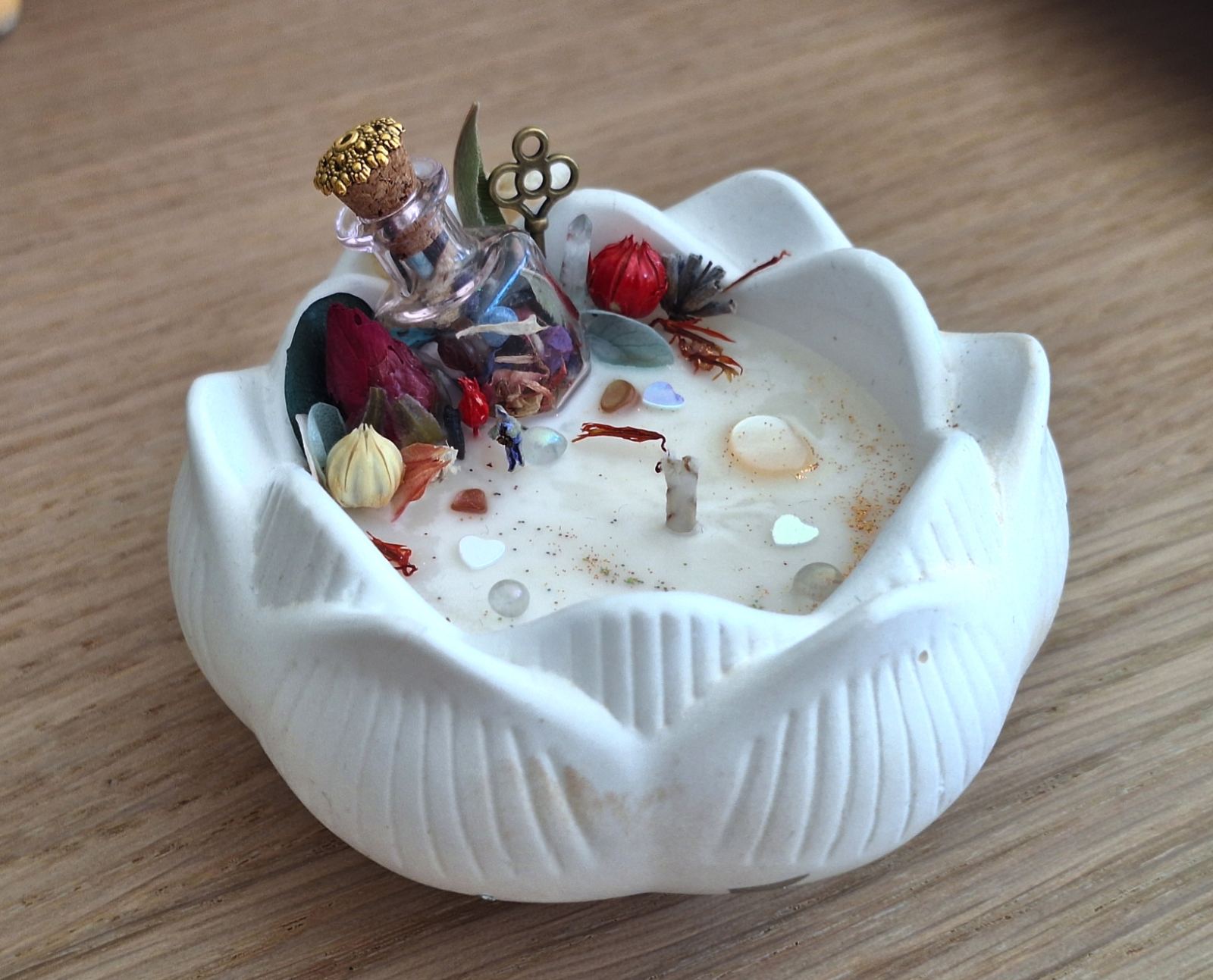 Bougie en forme de lotus blanche, fiole à bouchon doré et fleurs séchées