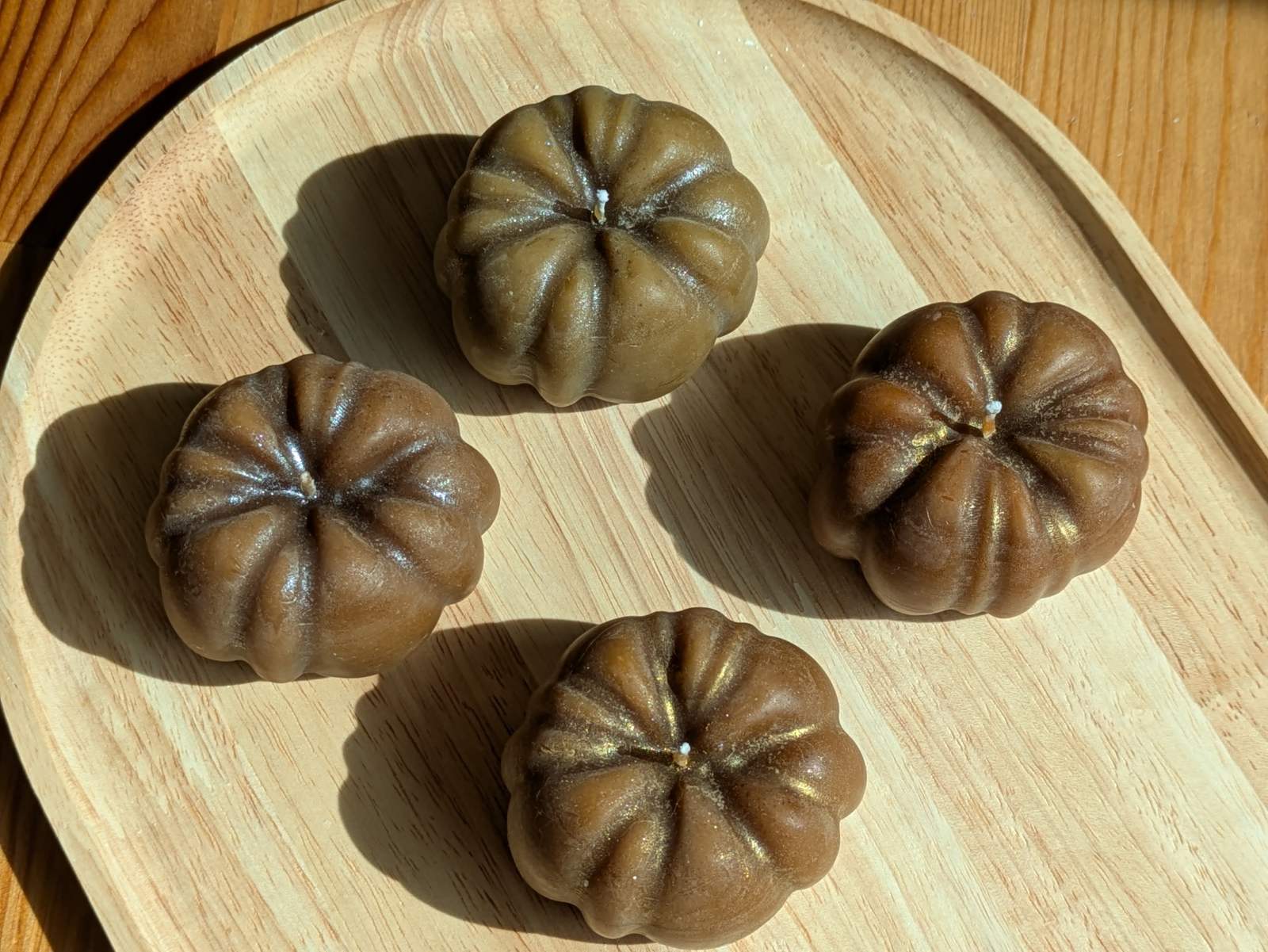 Quatre bougies en forme de citrouille en cire d'abeille naturelle disposées en cercle