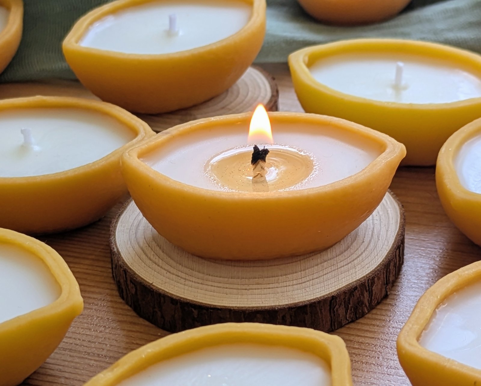 Bougie citron allumée sur une rondelle de bois, poussière dorée visible dans la cire de soja fondue, MonaLuna Candles
