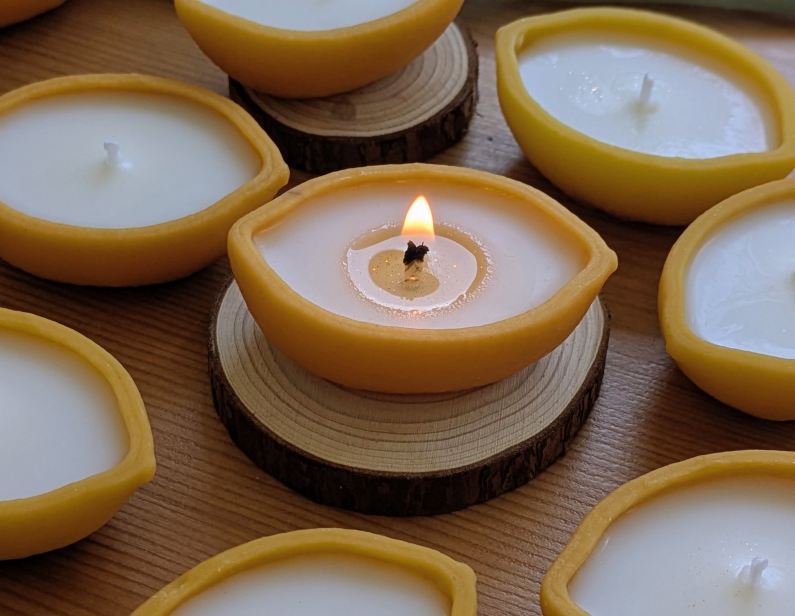 Bougie citron en cire d'abeille allumée, bain de cire de soja pailleté de poussière dorée, entourée de demi-citrons