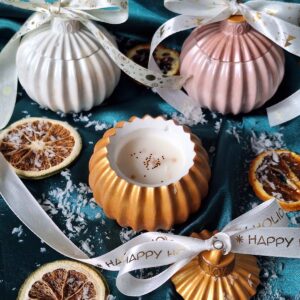 Bougie boule de Noël chic dorée, rose et blanche avec rubans, rondelles d'orange séchées sur un tissu vert