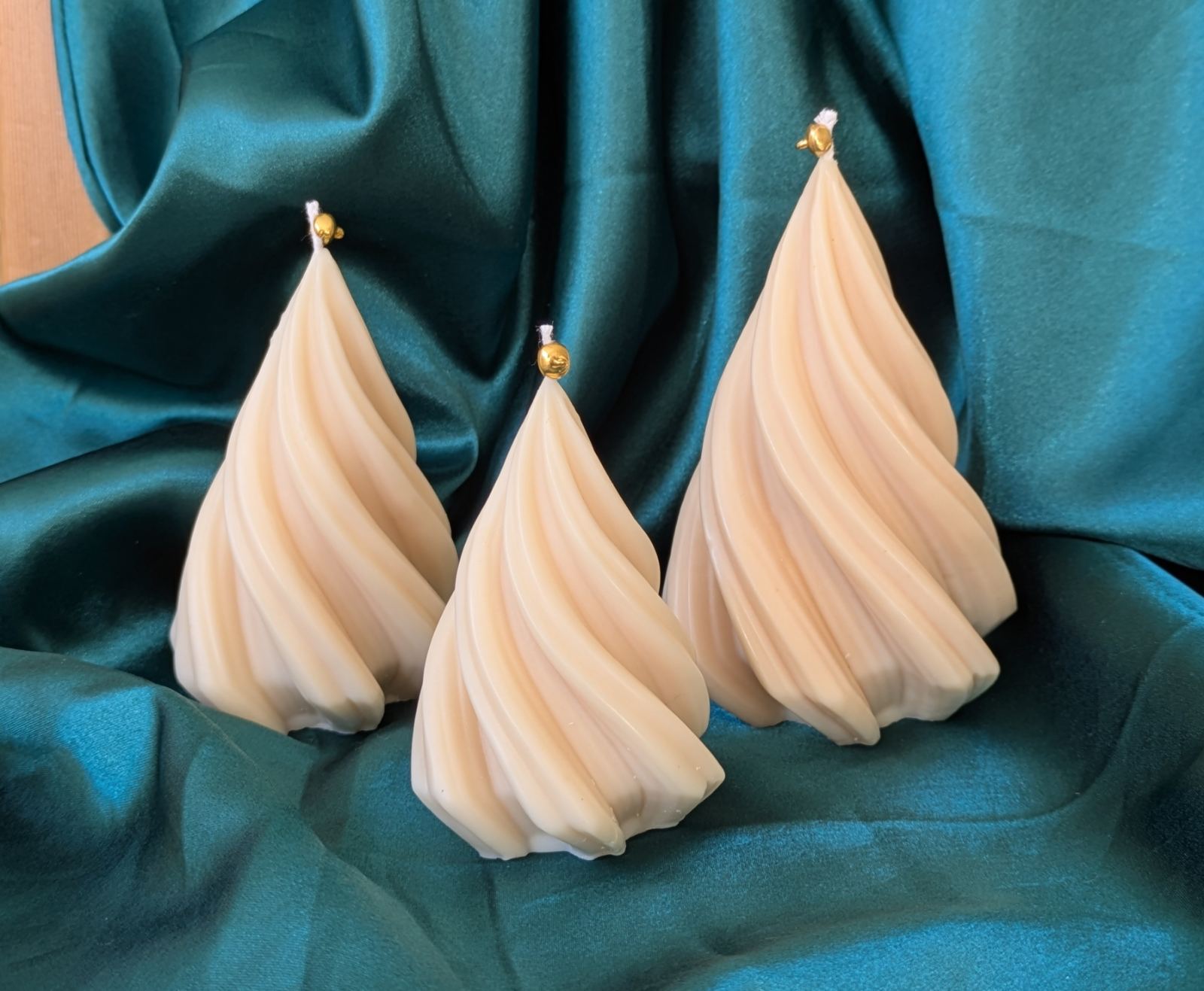 Trois bougies sapin torsadé de tailles différentes sur un tissu satiné bleu