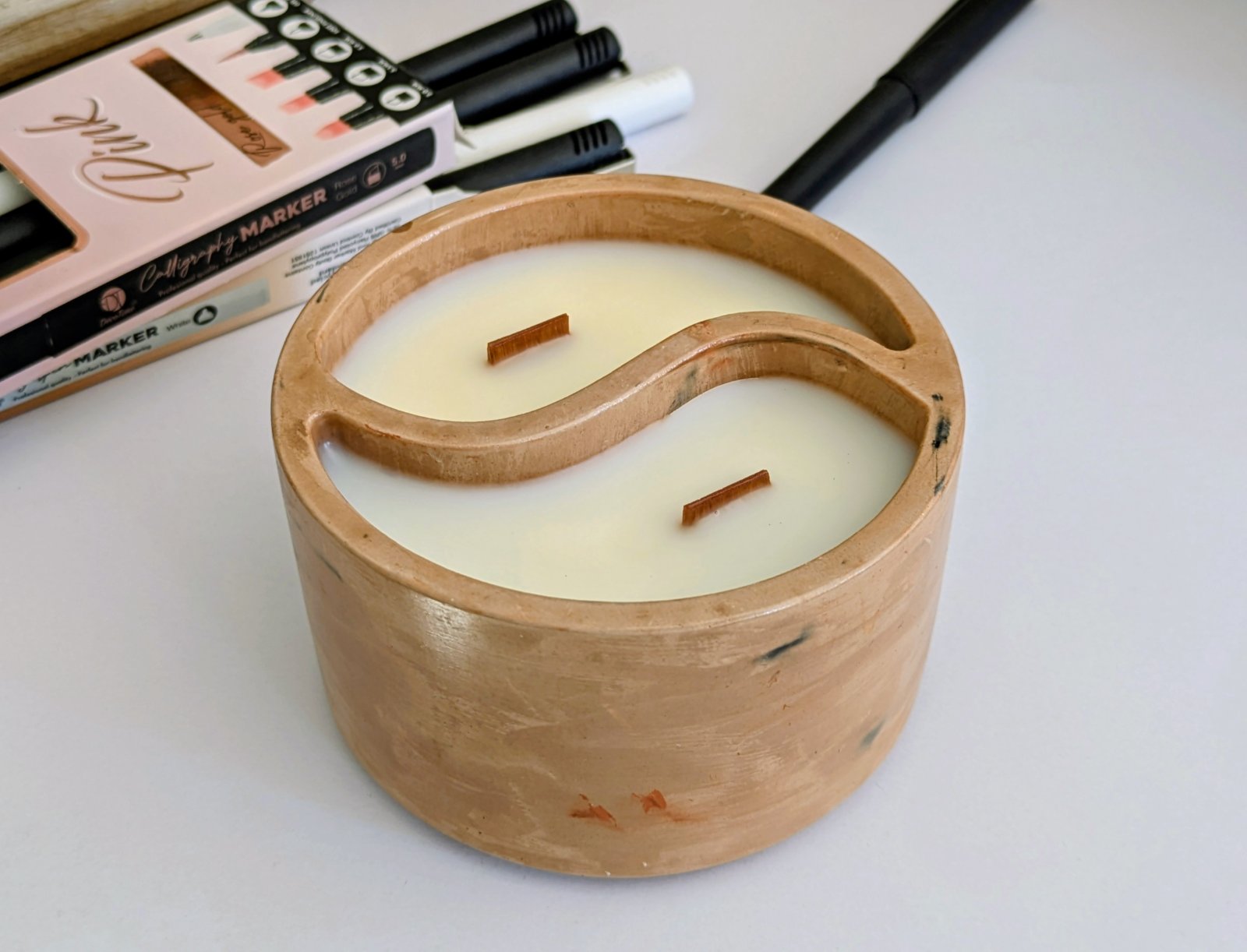Bougie yin yang en plâtre pêche marbré posée sur un bureau