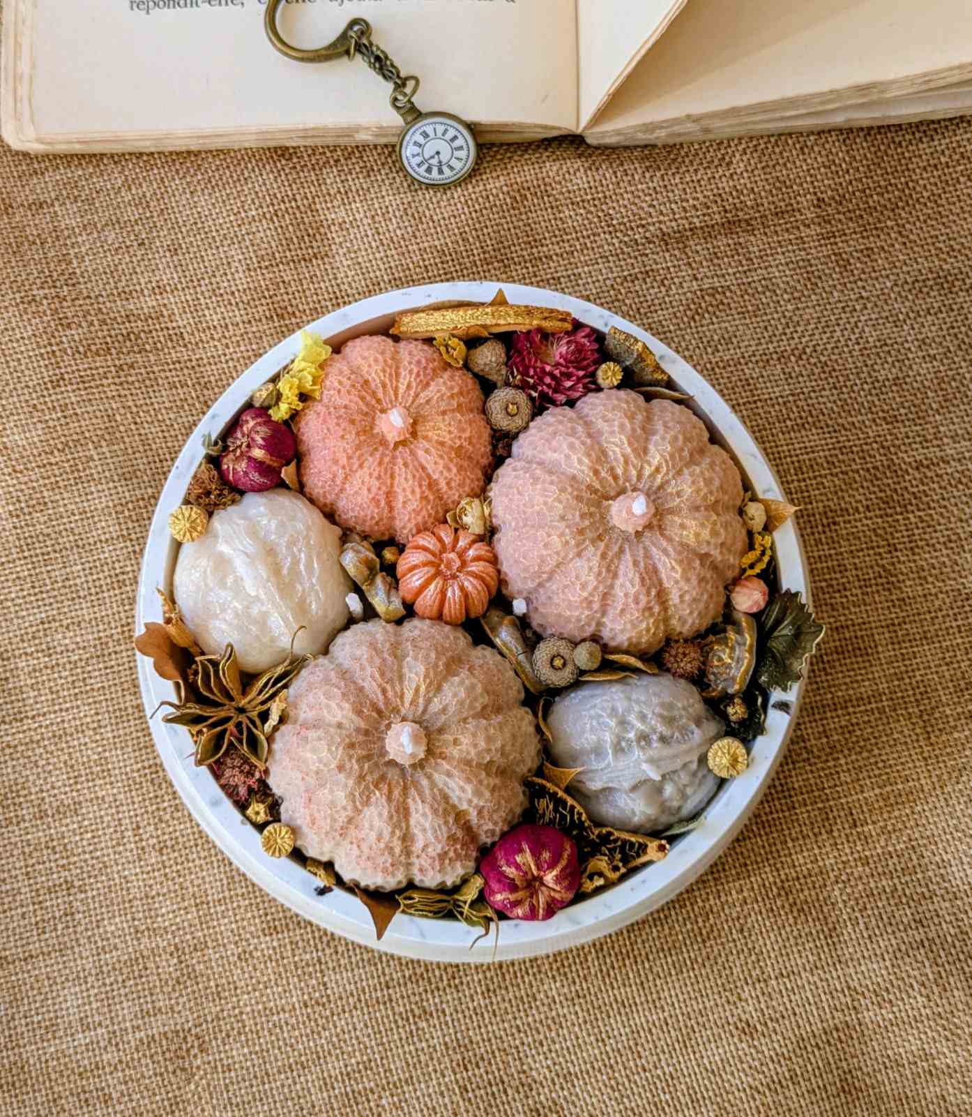 Bougie citrouille et noix vue de haut, badiane, agrumes séchés et petites fleurs en métal
