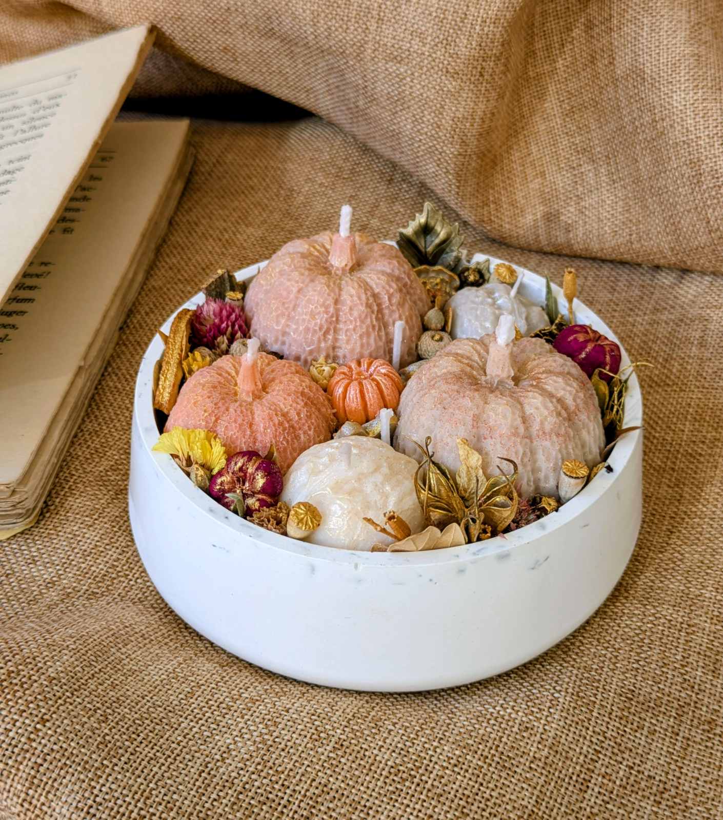Grande bougie citrouille et noix dans un bougeoir en plâtre blanc, fleurs et agrumes séchés