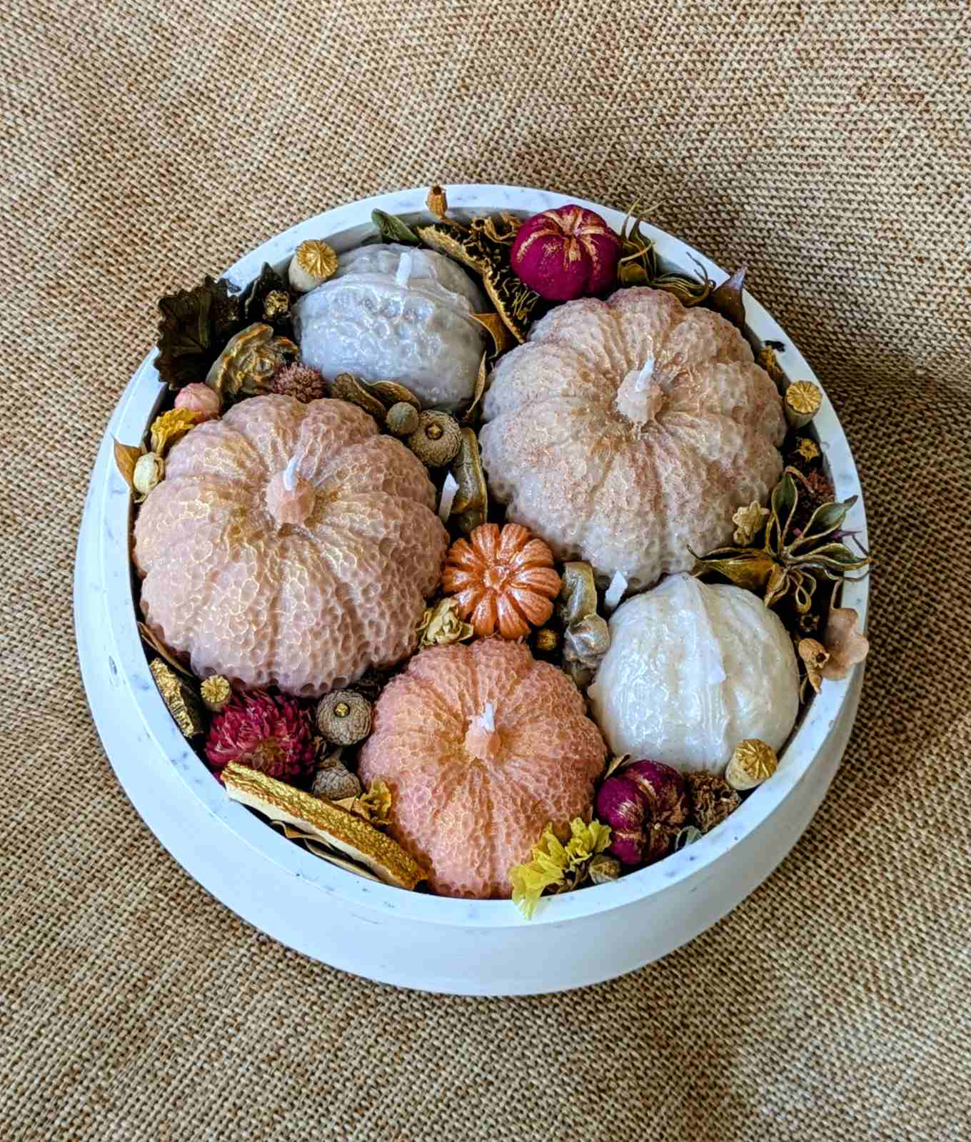 Bougie citrouille et noix vue du dessus, trois citrouilles roses et pêche et deux noix en cire de soja