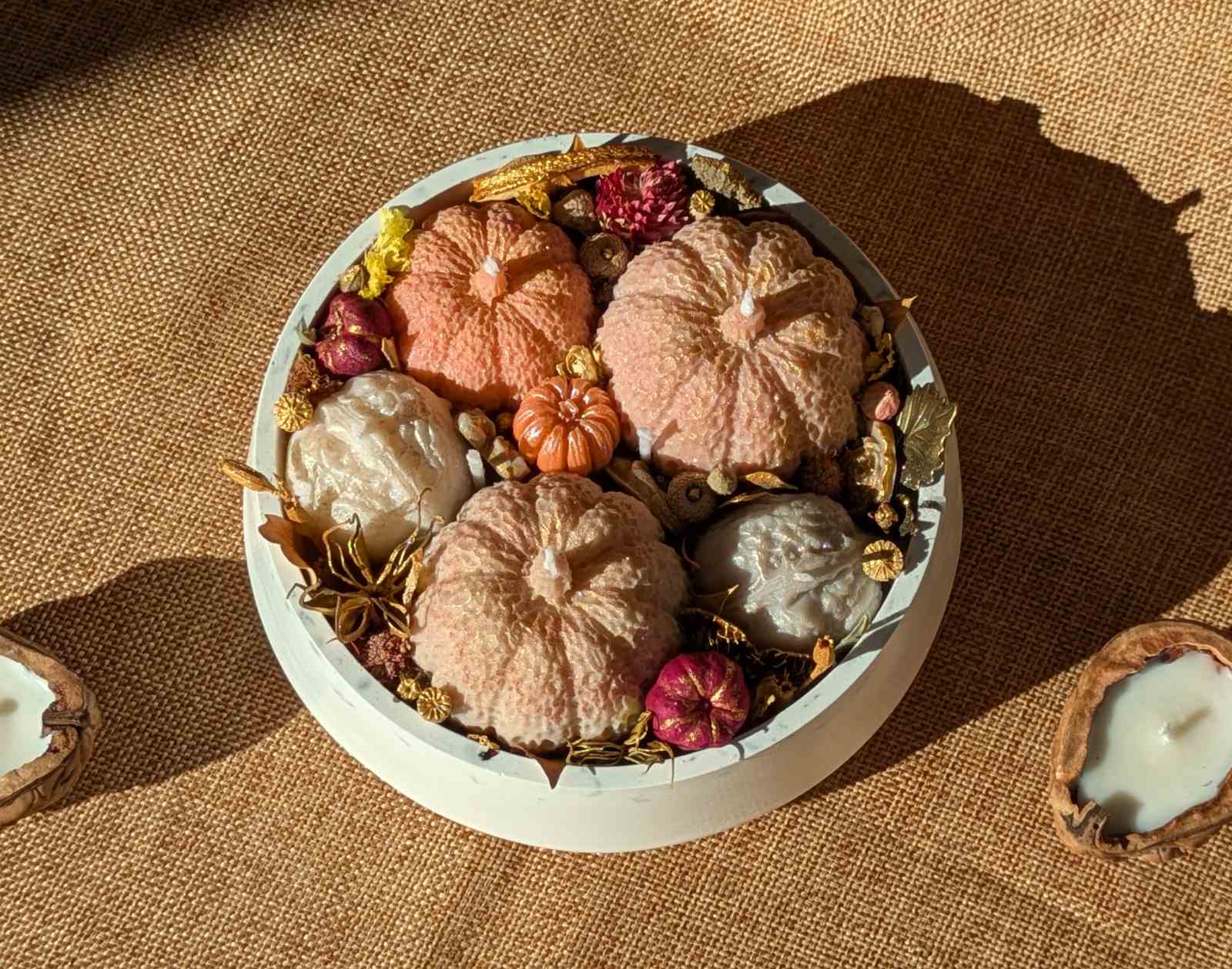 Composition de bougies citrouilles et noix au soleil, à côté d'une coque de noix